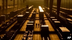 2024年1月3日，堪萨斯州埃杰顿，工人们在BNSF货运铁路联运码头的集装箱中间行走。（美联社照片）