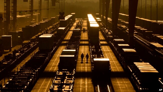 Workers walk among shipping containers at a BNSF intermodal terminal, Jan. 3, 2024, in Edgerton, Kansas. The nation’s employers added a robust 216,000 jobs in December 2023.