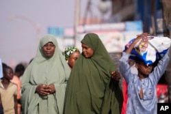 Para wanita menunggu di Kaduna, Nigeria, 8 Maret 2024. Pasukan keamanan menyapu hutan besar di wilayah barat laut Nigeria pada Jumat untuk mencari hampir 300 anak-anak yang diculik. (Foto: Sunday Alamba/AP Photo)