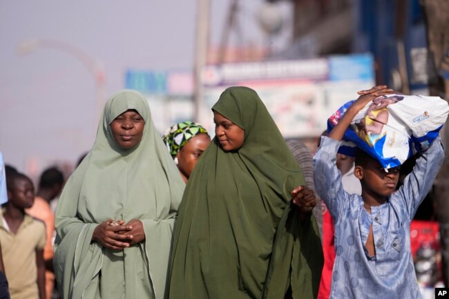 Para wanita menunggu di Kaduna, Nigeria, 8 Maret 2024. Pasukan keamanan menyapu hutan besar di wilayah barat laut Nigeria pada Jumat untuk mencari hampir 300 anak-anak yang diculik. (Foto: Sunday Alamba/AP Photo)