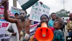 A woman with a baby joins a protest over economic hardship on a street in Lagos, Nigeria, Aug 5, 2024. 