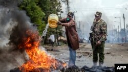 Mfanyikazi akimwaga maji kwenye kizuizi kinachowaka huko Nairobi, Julai 12, 2023. Picha na Luis Tato / AFP.