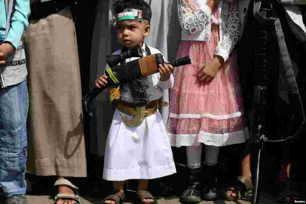 A boy carries a toy rifle during a demonstration against the continued Israeli offensive on the Gaza Strip, in Sanaa, Yemen.