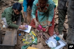 Korban selamat mencari barang-barang mereka dari rumah-rumah yang rusak akibat gempa di Distrik Rukum, barat laut Nepal, Senin, 6 November 2023. (AP/Niranjan Shrestha)