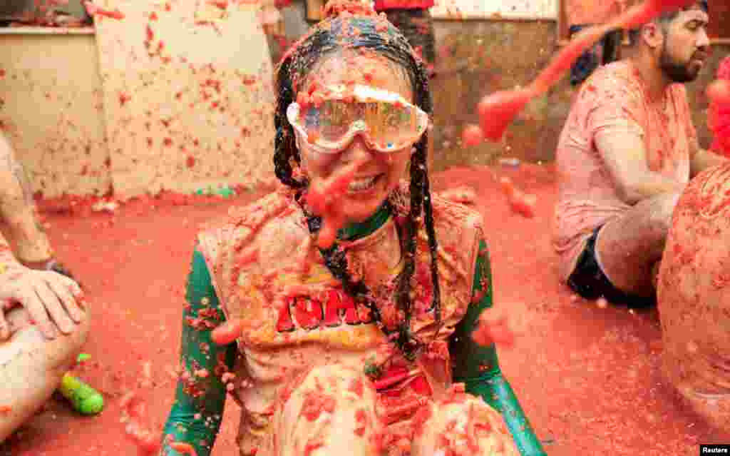 Una participante cubierta de pulpa de tomate observa mientras la gente asiste al festival anual de lucha contra la comida &quot;La Tomatina&quot; en Buñol, cerca de Valencia, España. &nbsp; 