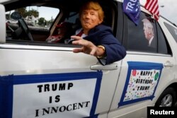 Raul Meneses mengenakan topeng yang menggambarkan mantan Presiden AS Trump saat berkumpul di Tropical Park, saat ia akan hadir di pengadilan federal atas tuduhan dokumen rahasia, di Miami, Florida, AS, 11 Juni 2023. (Foto: REUTERS/Marco Bello )