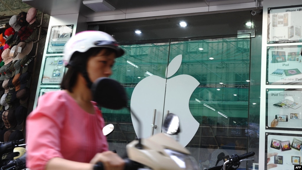 资料照：一名越南女子在河内骑电动车路过一家苹果专卖店。（2012年9月28日）(photo:VOA)