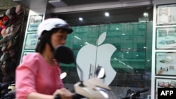 资料照：一名越南女子在河内骑电动车路过一家苹果专卖店。（2012年9月28日）