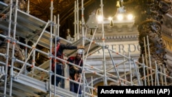 Para pekerja memasang perancah pada kanopi perunggu setinggi 29 meter karya Giovan Lorenzo Bernini di Basilika Santo Petrus di Vatikan, Rabu, 21 Februari 2024. (Foto: AP/Andrew Medichini)