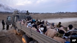 FILE - Israeli soldiers stand by a truck packed with bound and blindfolded Palestinian detainees, in Gaza, Dec. 8, 2023. 