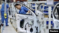 FILE - Employees work on assembling vehicles at a plant of SAIC Volkswagen in Urumqi, Xinjiang, China, on Sept. 4, 2018. (China Daily via Reuters)