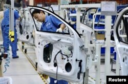 Para karyawan bekerja merakit kendaraan di pabrik SAIC Volkswagen di Urumqi, Daerah Otonomi Uyghur Xinjiang, China, 4 September 2018. (China Daily via Reuters)
