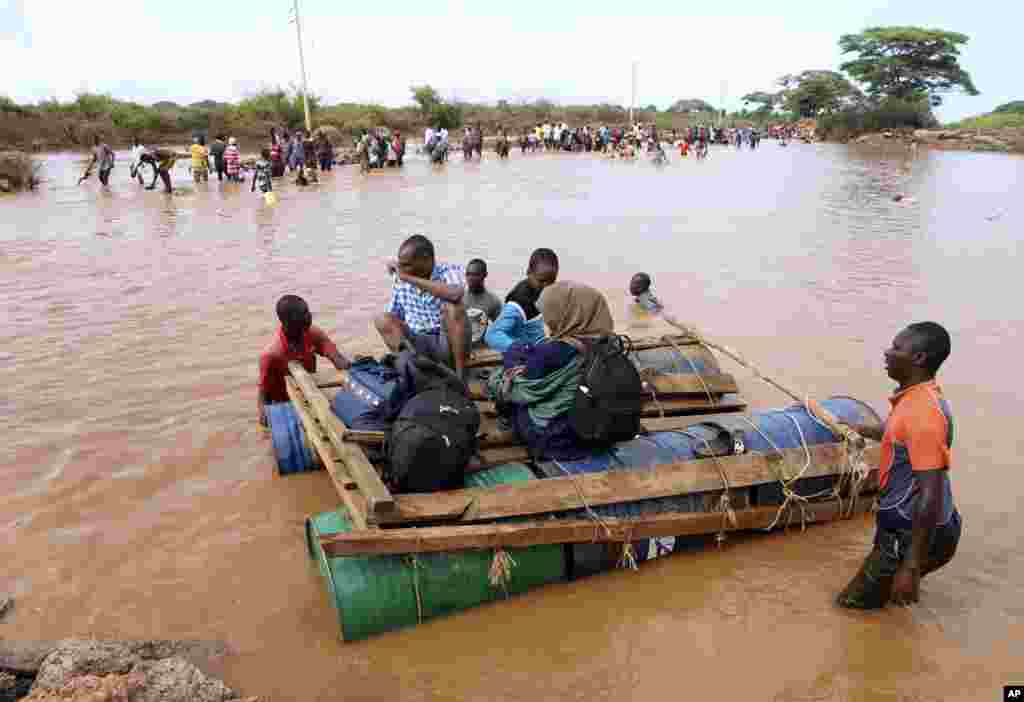 People cross a flooded area on makeshift floating tanks at Mororo, border of Tana River and Garissa counties, North Eastern Kenya.