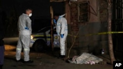 Police stand near a covered body in the Angelo settlement in Boksburg, South Africa, July 6, 2023. 