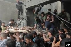 Warga Palestina membawa jenazah yang ditemukan di bawah reruntuhan rumah yang hancur pasca serangan udara Israel di kamp pengungsi Khan Younis, Jalur Gaza selatan, 18 November 2023. (Foto: AP)