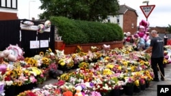 A man waters the floral tribute in Southport, Aug. 5, 2024 after three young girls were killed in a knife attack at a Taylor Swift-themed holiday club last week.