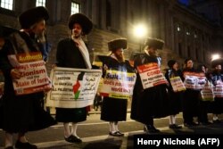 Članovi ultraortodoksne jevrejske zajednice drže plakate dok učestvuju u Nacionalnom maršu za Palestinu u centru Londona 9. decembra 2023.