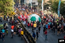 Masyarakat berkerumun di jalan untuk menyaksikan sepak bola raksasa yang digulirkan dalam acara "Trophy Experience" di Surabaya pada 29 Oktober 2023, jelang dimulainya turnamen sepak bola FIFA U17 2023. (Foto: JUNI KRISWANTO/AFP)