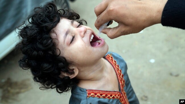 A health worker administers a polio vaccine to a child in a neighborhood of Lahore, Pakistan, Nov. 27, 2023.