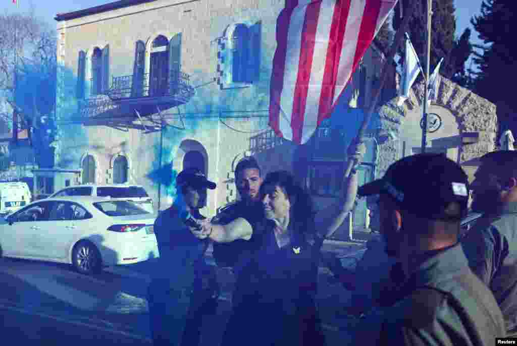 A woman holds a flag and a blue smoke bomb as protesters demonstrate outside the U.S. Consulate in Jerusalem, calling on U.S. President Joe Biden to broker a deal to release hostages being held by Hamas in Gaza.