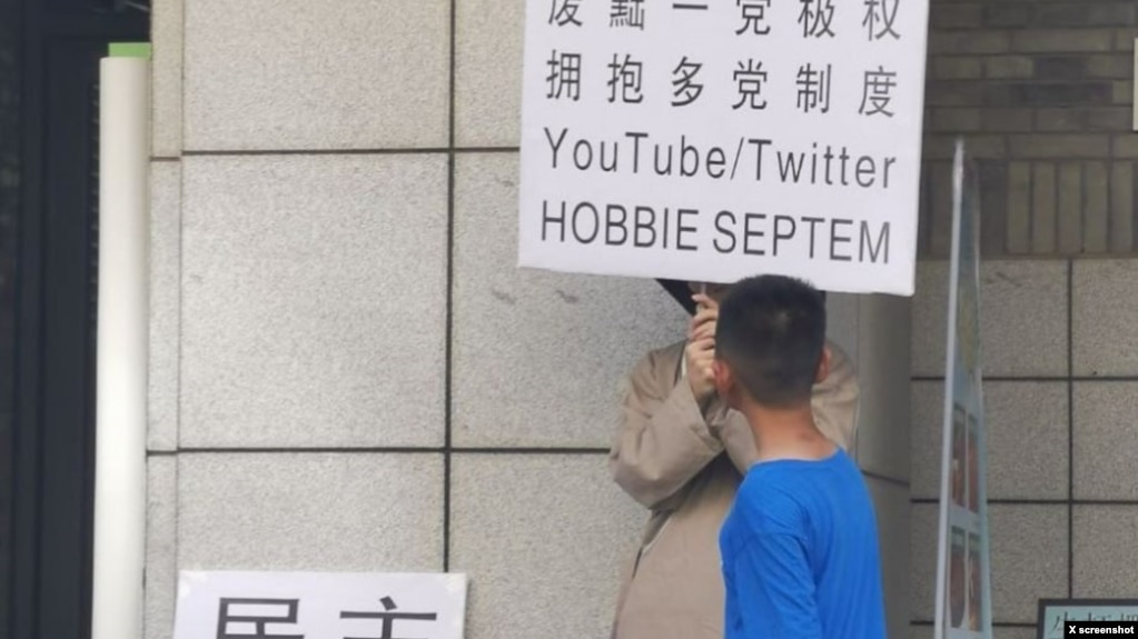 2023年6月22日,网传北京大学一食堂门外有年轻人举牌呼唤民主革命和多党制取代一党极权。(推特图片)