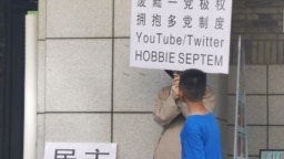 2023年6月22日，网传北京大学一食堂门外有年轻人举牌呼唤民主革命和多党制取代一党极权。（推特图片）