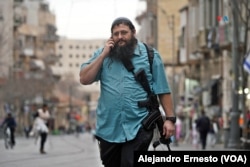 Personas con atuendos de civil portan armas automáticas. Se trata de una escena cotidiana en Jerusalén.