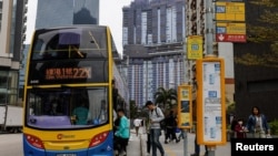 香港居民在一处住宅楼建筑工地前排队上公交车。（2024年2月27日）