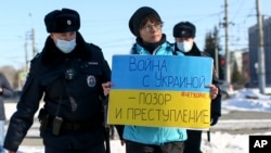 FILE - Police detain a demonstrator with a poster which reads "The war with Ukraine is a shame and a crime" during an action against Russia's attack on Ukraine in Omsk, Russia, Feb. 27, 2022. 