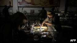 A seller tends to a customer at a supermarket during a blackout in Kyiv, Ukraine, Aug. 30, 2024.