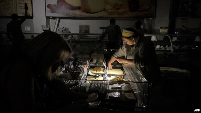 A seller tends to a customer at a supermarket during a blackout in Kyiv, Ukraine, Aug. 30, 2024.
