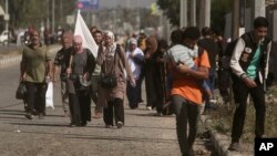 Una mujer porta una bandera blanca para evitar que le disparen, mientras los palestinos huyen de la ciudad de Gaza hacia el sur de la Franja de Gaza en la calle Salah al-Din en Bureij, el martes 7 de noviembre de 2023. (Foto AP/Mohammed Dahman)