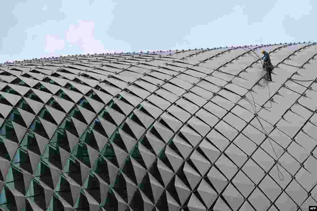 Workers clean the roof dome of the Esplanade Theatres on the Bay in Singapore.