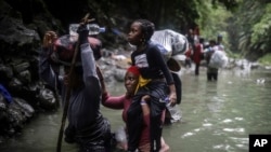 FILE - Haitian migrants wade through a river as they cross the Darien Gap from Colombia to Panama in hopes of reaching the United States, May 9, 2023. (AP Photo/Ivan Valencia)