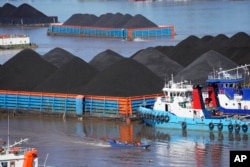 FILE - Kapal-kapal berlayar di dekat tongkang yang penuh dengan batu bara di sungai Mahakam, Samarinda, Kalimantan Timur, 19 Desember 2022. (Dita Alangkara/AP)