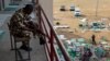 FILE - A day after the elections, a soldier guards a vote collation center that had been stormed by unknown assailants earlier in the day in Alimosho, Lagos, Nigeria on Feb. 26, 2023.