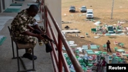 FILE - A day after the elections, a soldier guards a vote collation center that had been stormed by unknown assailants earlier in the day in Alimosho, Lagos, Nigeria on Feb. 26, 2023.