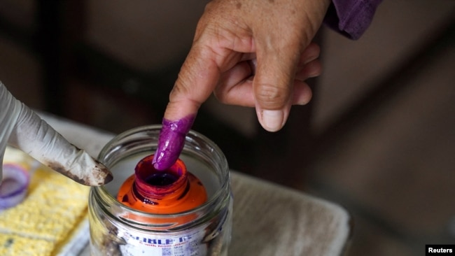 A person dips their finger in ink at a Phnom Penh, Cambodia, polling station during Cambodia's general election, July 23, 2023. A recent report by Freedom House highlighted Cambodia as one of the places that experienced attempts to control, hinder or interfere with elections.