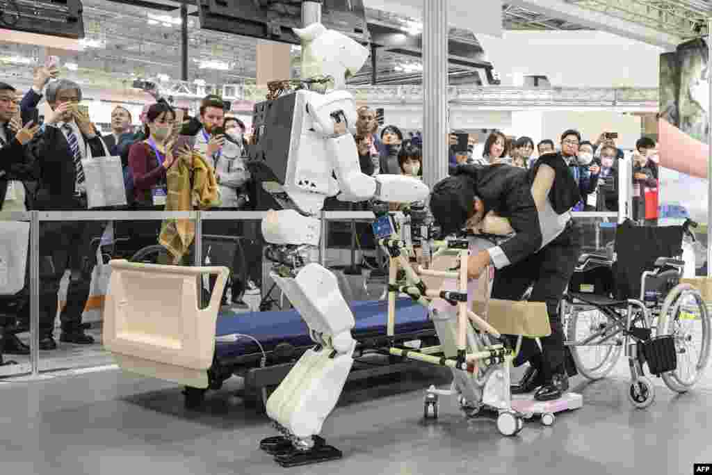 A robot helps move a man into a wheelchair during a demonstration at the Kawasaki booth on the first day of the 2023 International Robot Exhibition at the Tokyo International Exhibition Center in Tokyo, Japan. (Photo by Richard A. Brooks / AFP)