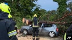 Firefighters remove tree branches from a damaged car after a powerful storm in Zagreb, Croatia, July 19, 2023. Another storm swept through the Balkans on July 21, 2023, and killed three people in Serbia.