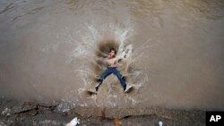 A boy jumps into a canal on a hot day in Jammu, India, June 20, 2023. Many parts of India are experiencing scorching heat this summer. 