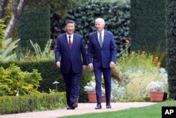 FILE - President Joe Biden and China's President President Xi Jinping walk in the gardens at the Filoli Estate in Woodside, California, Nov. 15, 2023.