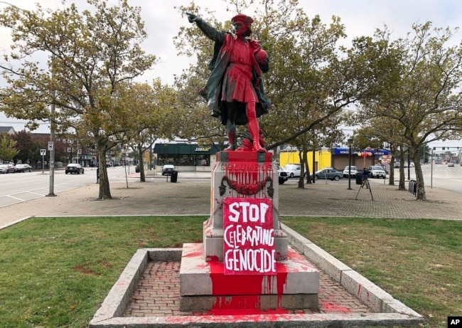 FILE - In this Oct. 14, 2019, file photo, a sign reading "stop celebrating genocide" sits at the base of a statue of Christopher Columbus in Providence, R.I., after it was vandalized with red paint. (AP Photo/Michelle R. Smith, File)