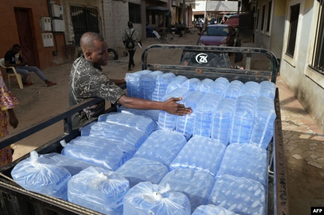 FILE - A man loads plastic sachets filled with drinkable water for delivery in Dakar, on Aug. 23, 2023.