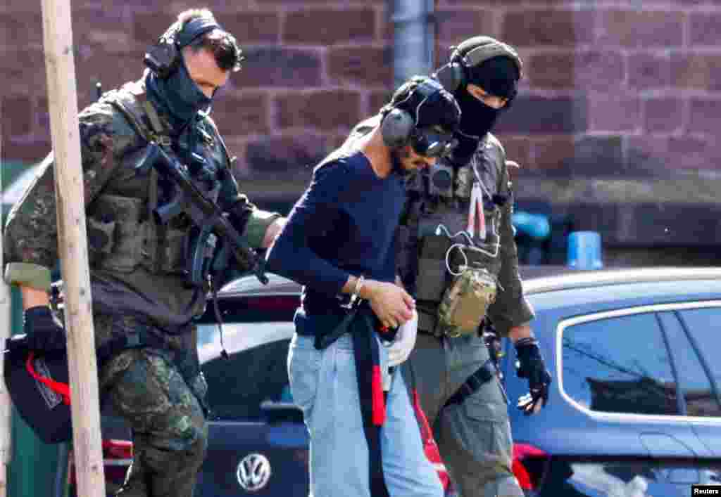 A 26-year-old Syrian man, who is the suspect of a stabbing rampage in the western German city of Solingen in which several individuals were killed, is escorted by police as he leaves the Federal Public Prosecutor in Karlsruhe.