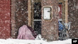 Two people take cover in an entryway of a downtown restaurant Nov. 9, 2023, in Anchorage, Alaska.
