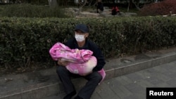 北京一家兒童醫院外一名男子懷抱一個幼童。（2023年11月27日）