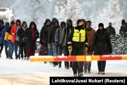 FILE - Finnish Border Guards escort the migrants at the international border crossing at Salla, northern Finland, Nov. 23, 2023. (Lehtikuva/Jussi Nukari via Reuters)