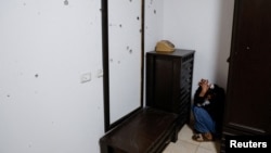 Masa, anak perempuan yang saudaranya terbunuh dalam serangan Israel, duduk bersembunyi di samping tembok yang rusak akibat lubang peluru, di rumah mereka, dekat kota Jenin, Tepi Barat yang diduduki Israel, Kamis (25/1). (Reuters) 