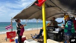 FILE - Jordan Ruidas, left, speaks to people at the Fishing for Housing camp on Kaanapali Beach in Lahaina, Hawaii, Nov.14, 2023.